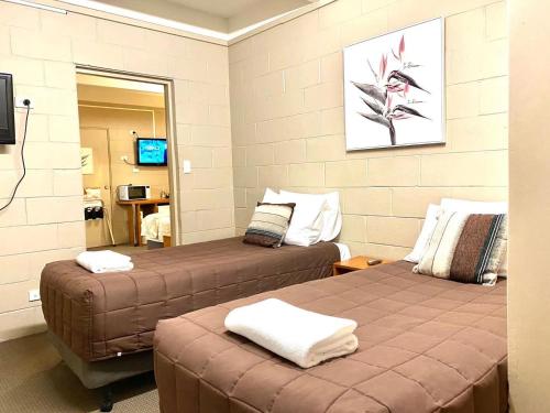 a room with two beds and a television at Apollo Motel Parkes in Parkes