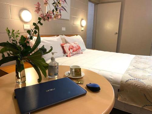 a laptop on a table next to a bed at Apollo Motel Parkes in Parkes