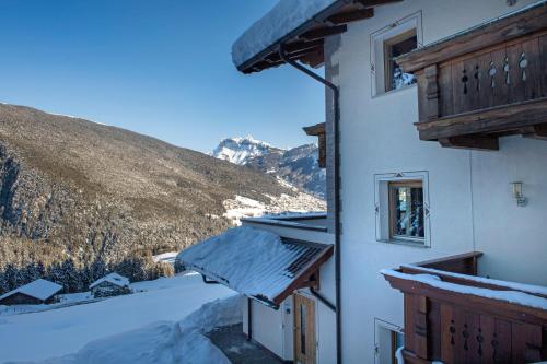 a building with snow on the ground next to a mountain at Chalet Alpina in Ortisei