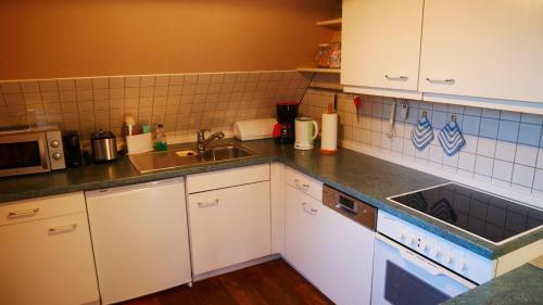 a kitchen with white cabinets and a sink at Haus "Zur Seebrücke" - Deichblick in Zingst