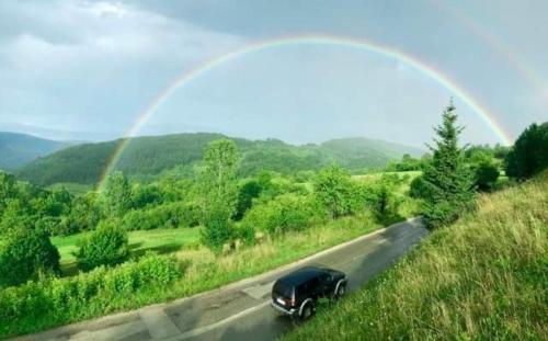 a black car driving down a road with a rainbow at Vila Panic in Pirot