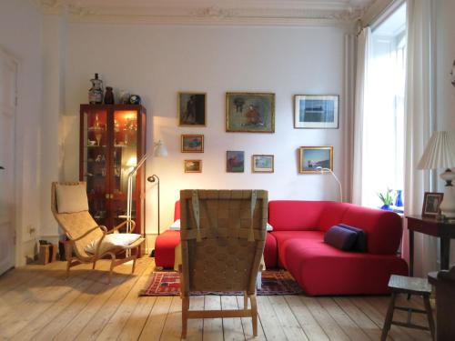ein Wohnzimmer mit einem roten Sofa und Stühlen in der Unterkunft ApartmentInCopenhagen Apartment 931 in Kopenhagen