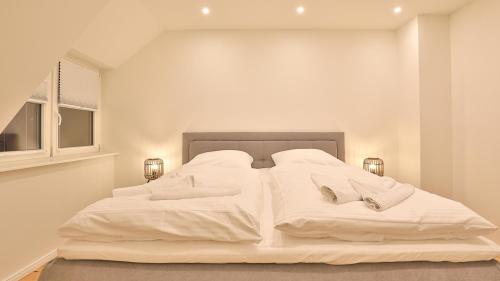 a white bed with white sheets and slippers on it at Jade 2 in Born