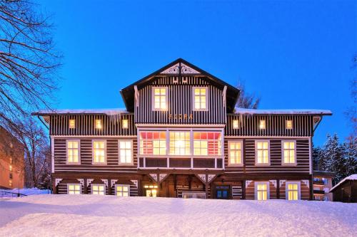 a large wooden house with snow on the ground at Penzion Flora in Janske Lazne