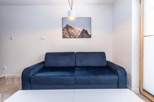 a blue couch in a living room with a picture on the wall at TatryTop Apartamenty Alpejski SPA in Kościelisko