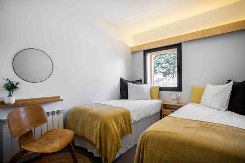 a room with two beds and a chair and a mirror at Finca el Veinti9 in Navacerrada
