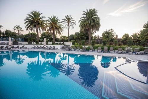 a large swimming pool with palm trees and chairs at Azoris Royal Garden – Leisure & Conference Hotel in Ponta Delgada