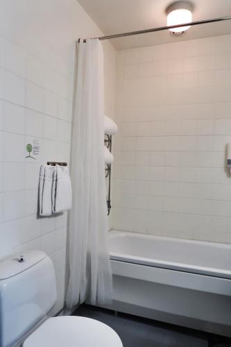 a white bathroom with a toilet and a bath tub at Hotell Roslagen by Atomis Hotels in Norrtälje