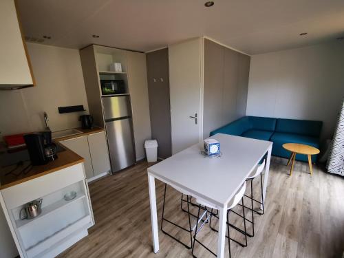 Habitación pequeña con mesa blanca y sofá azul en Camping des Bondons, en La Ferté-sous-Jouarre