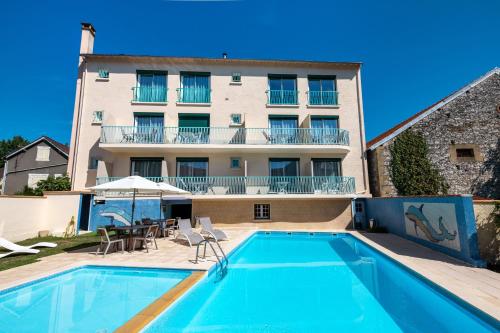 a hotel with a swimming pool in front of a building at Le Quercy in Souillac