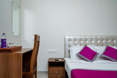 a bedroom with a large bed with purple pillows at Nexstay Treats Inn in Kozhikode