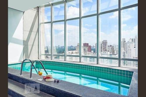 a swimming pool in a building with a large window at FLAT Jardins São Paulo excelente! in Sao Paulo