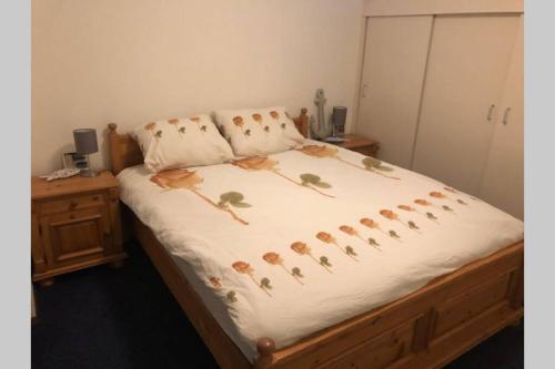uma cama com um cobertor branco com flores em Bij de duinen 300 meter van de zee gratis wifi huisdieren toegestaan thuiswerkplek em Julianadorp