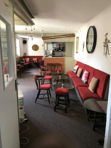 a waiting room with a red couch and tables and chairs at The Denewood in Sandown