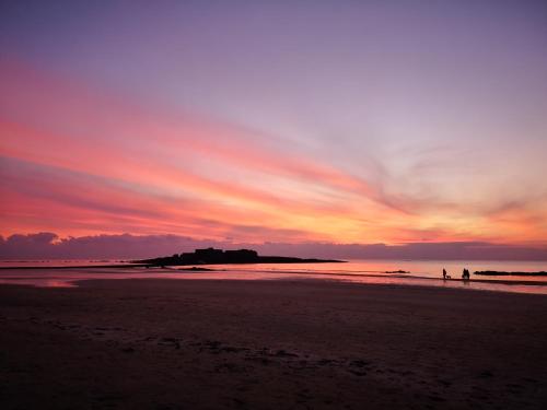 zwei Menschen, die bei Sonnenuntergang am Strand spazieren gehen in der Unterkunft L'horizon - Bord de mer in Ploemeur