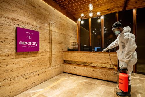 a man in a mask is standing in front of a counter at Nexstay Treats Inn in Kozhikode