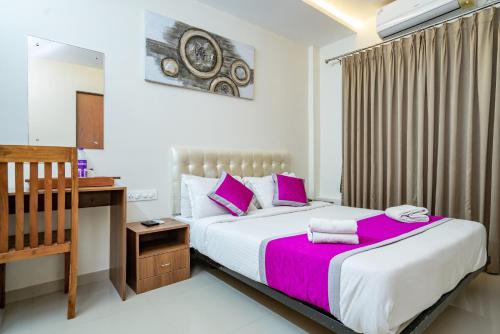 a bedroom with a large bed with pink pillows at Nexstay Treats Inn in Kozhikode