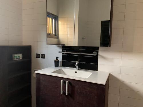 ein Bad mit einem Waschbecken und einem Spiegel in der Unterkunft Villa Luxury Baguida in Lomé