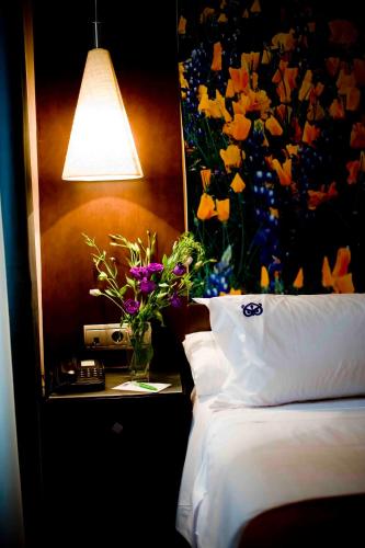 a bed with a vase of flowers on a table with a lamp at Suites Gran Vía 44 in Granada
