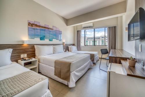 um quarto de hotel com duas camas e uma televisão de ecrã plano em Tambaqui Praia Hotel em Maceió