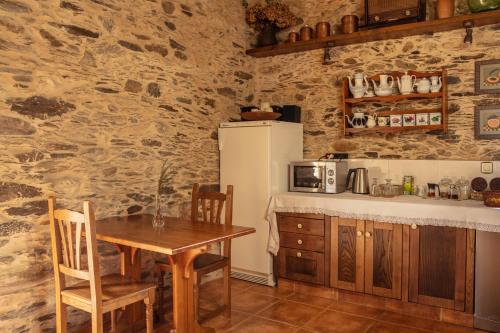 a kitchen with a table and a refrigerator at Lugar del Rio in Couzadoiro