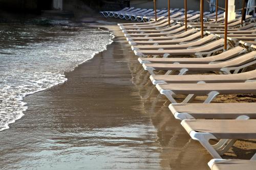 a row of white lounge chairs on a beach at InterContinental Malta by IHG in St Julian's