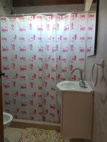 a bathroom with a shower curtain with a sink at Cabañas Mangata in Mar de Cobo