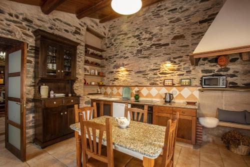 a kitchen with a table and chairs and a stone wall at Lugar del Rio in Couzadoiro