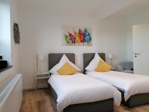 Cette chambre comprend 2 lits avec des murs blancs et des oreillers jaunes. dans l'établissement Gästezimmer Bergerhof - Ankommen und Wohlfühlen, à Neuss