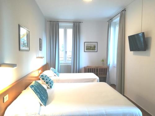 Cette chambre comprend 2 lits et une télévision. dans l'établissement Hotel Quarcino, à Côme