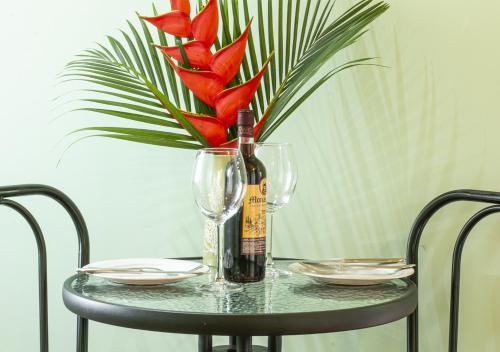 a table with a bottle of wine and a vase with red flowers at Cabañas Río Escondido en La Fortuna in Fortuna