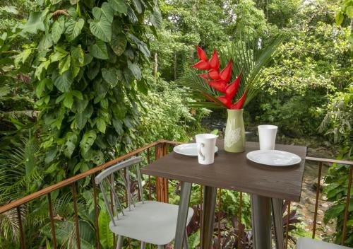 a table with red flowers in a vase on a balcony at Cabañas Río Escondido en La Fortuna in Fortuna