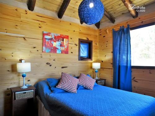 Un dormitorio con una cama azul con dos almohadas. en OHANA, en Punta del Diablo