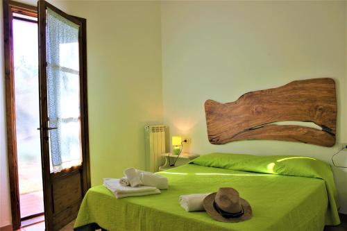 Schlafzimmer mit einem grünen Bett mit einem Kopfteil aus Holz in der Unterkunft Agriturismo Arundineto Valle - by Bolgheri Holiday in Castagneto Carducci