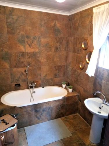 a bathroom with a tub and a sink at Edenville Guesthouse in Lichtenburg