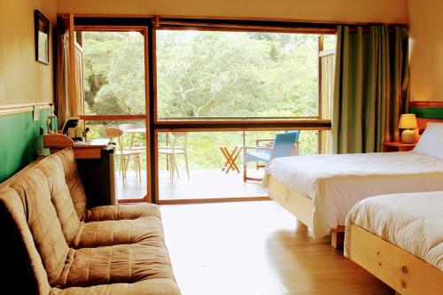 a bedroom with two beds and a couch and a window at Hotel Pibi Boreal in Alajuela City