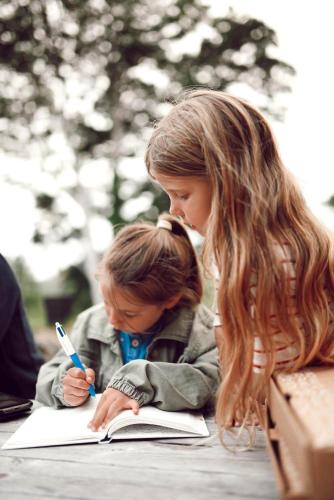 two little girls are writing in a book at Glamping Yurts near Newquay in Newquay