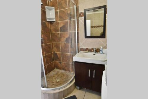 a bathroom with a shower and a sink and a mirror at 12 Settler Sands Beachfront cottage with sea view in Port Alfred