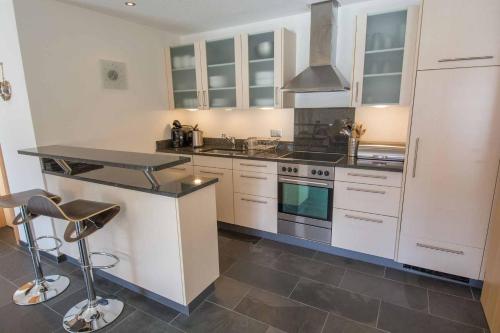 a kitchen with white cabinets and a stove top oven at Ferienwohnung Schützenrain in Adelboden