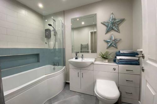 a bathroom with a sink and a toilet and a bath tub at Modern and spacious open plan bungalow in Felixstowe