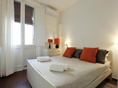a white bedroom with a large bed with orange pillows at UR-NEST Montegrappa in Bologna