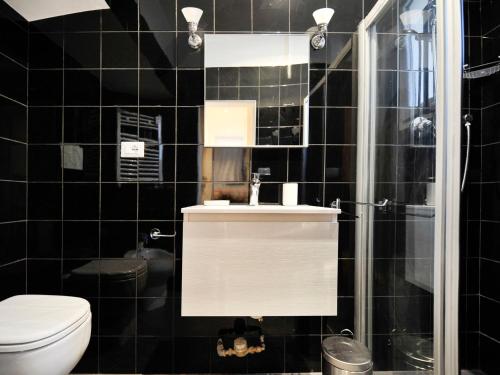 a black tiled bathroom with a toilet and a sink at UR-NEST Montegrappa in Bologna
