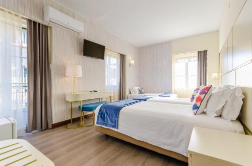 リスボンにあるオテル LX ロシオの大きなベッドとデスクが備わるホテルルームです。