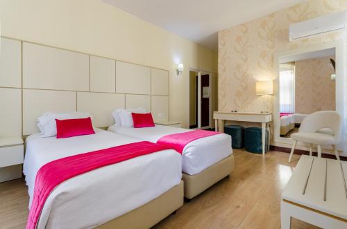 a hotel room with two beds with red pillows at Hotel LX Rossio in Lisbon