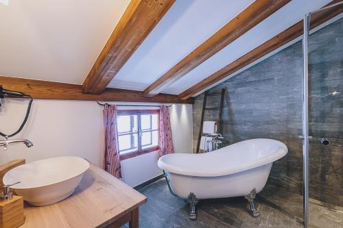 ein Badezimmer mit einer großen Badewanne und einer Glasdusche in der Unterkunft AlpenOase Sonnhof in Saalbach-Hinterglemm