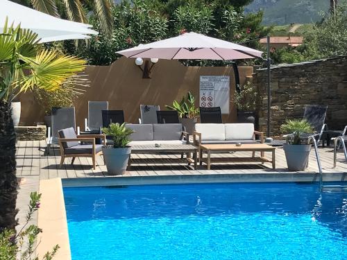 a swimming pool with a table and an umbrella and chairs and a table and chairs at Auberge le Montana in Saint-Florent