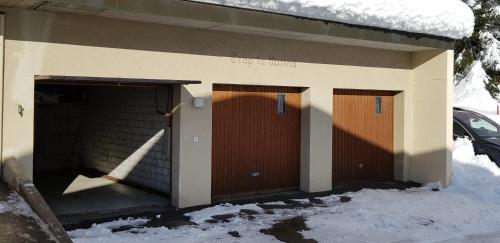 a garage with two brown doors in the snow at El Cantun - 7 Zimmer Einfamilienhaus mit 200m2 in Flims