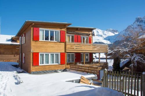 a wooden house in the snow with a fence at Chalet Azeno OG in Adelboden