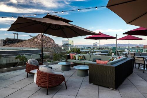 a patio with couches and tables and umbrellas at Hyatt Place Tempe Phoenix University in Tempe