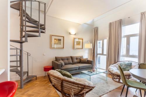 sala de estar con sofá y escalera de caracol en MIT House Barquillo Duplex en Madrid, en Madrid